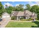 View of home with three-car garage and lush green lawn and landscaping at 132 Copper Hills Dr, Canton, GA 30114