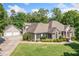 Charming home featuring a detached garage, lush lawn, and complemented by surrounding trees at 132 Copper Hills Dr, Canton, GA 30114
