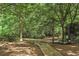 Secluded backyard with mature trees, a wooden walkway, and natural landscaping, offering a peaceful retreat at 1832 Gordon Ne Mnr, Atlanta, GA 30307