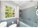 Classic bathroom with blue tiling, tub-shower combo, and window overlooking the lush greenery at 45 Michelle Ne Cir, Atlanta, GA 30342