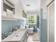 Well-lit bathroom with blue tile, modern sink, tub-shower combo, and view of the greenery outside at 45 Michelle Ne Cir, Atlanta, GA 30342