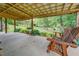 Inviting back porch with wooden swing, lush landscaping, and a serene view, perfect for relaxation at 75 Puppy Chase, Social Circle, GA 30025