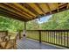 Relaxing covered deck area, complete with wooden furniture, railing and a serene view of the backyard at 75 Puppy Chase, Social Circle, GA 30025