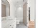 Well-lit bathroom with white vanity, arched mirror, penny tile flooring, and tiled shower at 1084 Wrights Mill Rd, Canton, GA 30115