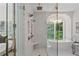 Bright bathroom featuring double shower heads, a standalone tub, chandelier, and large window overlooking a wooded landscape at 1084 Wrights Mill Rd, Canton, GA 30115
