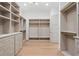 Elegant walk-in closet with light hardwood floors, custom shelving, drawers, and rod space at 1084 Wrights Mill Rd, Canton, GA 30115