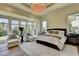 Luxurious main bedroom with a tray ceiling, modern chandelier, and a sitting area overlooking the backyard at 2305 Braselton Hwy, Buford, GA 30519