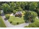 Stunning aerial view of a two-story home with a circular driveway and lush green lawn surrounded by mature trees at 3310 Chartwell Blvd, Suwanee, GA 30024