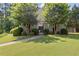 Charming home exterior with lush green lawn, mature trees, and a welcoming entrance gate at 3310 Chartwell Blvd, Suwanee, GA 30024
