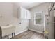 Well-lit laundry room includes a utility sink, storage cabinets and modern water heater at 3310 Chartwell Blvd, Suwanee, GA 30024