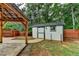 White backyard shed near a covered patio and a brown wooden fence at 425 Charlyne Way, Dacula, GA 30019