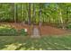 Wooded backyard with a staircase leading uphill, featuring mature trees and shrubs at 6034 Addington Nw Dr, Acworth, GA 30101