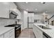 Well-lit kitchen with white cabinetry, a black gas range, and stainless appliances at 5452 Fountainhead Ln, Auburn, GA 30011