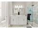 Bathroom featuring white cabinets, dual sinks, framed mirrors, and a glass enclosed shower at 4143 N Swann St, Covington, GA 30014