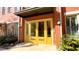 Inviting red brick townhome featuring a bright yellow front door, decorative sconces, and trimmed landscape at 4143 N Swann St, Covington, GA 30014