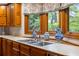 Kitchen featuring stainless steel sink, faucet, backsplash, wood cabinets, and stylish vases at 44 Muscogee Nw Ave, Atlanta, GA 30305