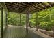 Covered patio with wood floors, comfortable swing chair, and lush green surroundings, ideal for outdoor relaxation at 1860 Mountain Shadow, Stone Mountain, GA 30087