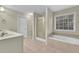 Bathroom featuring double vanity sinks, a glass shower, and a soaking tub with a large window at 1558 Park Knoll Trl, Lawrenceville, GA 30043