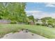 Large backyard with a wooden swing set and a concrete patio, surrounded by lush greenery and a wooden fence at 5555 Sugar Crossing Dr, Sugar Hill, GA 30518