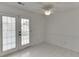 Bright sunroom with white paneled walls, white tile floor, and french doors to the backyard at 5555 Sugar Crossing Dr, Sugar Hill, GA 30518
