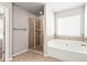 Bright bathroom featuring tiled shower with glass door and separate soaking tub and tile surround at 12348 Hillcrest Dr, Hampton, GA 30228