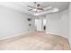 Spacious bedroom featuring neutral walls, carpet, a tray ceiling with fan, and an ensuite bath and door at 12348 Hillcrest Dr, Hampton, GA 30228