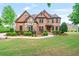Well-manicured lawn and landscaping highlight the brick and stone facade of this beautiful home at 2400 Gants Hill Pl, Cumming, GA 30041