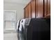 Laundry room with dark wood cabinets above the black washer and dryer near window at 4884 Kentwood Dr, Marietta, GA 30068