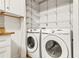Convenient laundry closet with full-size, white washer and dryer, and shelving for storage at 228 Smokerise Se Cir, Marietta, GA 30067
