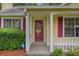 Welcoming front porch featuring colorful red shutters, a decorative door, and maintained landscaping at 2631 Rolling Hills Way, Conyers, GA 30094