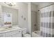A bathroom featuring a shower-tub combo with gray and white striped shower curtain, white vanity, and decorative wall art at 3332 Old Concord Se Rd, Smyrna, GA 30082