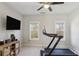 An exercise room featuring a ceiling fan, a wall-mounted TV, a treadmill, two windows, and a storage console at 3332 Old Concord Se Rd, Smyrna, GA 30082
