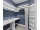 This blue laundry room includes a desk, storage shelves, a hanging rod with a curtain, and slate tile flooring at 1206 Kincaid Rd, Marietta, GA 30066