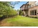 Lush green backyard with manicured lawn, bordered by trees, and black metal fence; two-story home in background at 580 Grimsby Ct, Suwanee, GA 30024