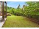 A spacious, well-manicured backyard with lush green lawn, bordered by trees, and a black metal fence at 580 Grimsby Ct, Suwanee, GA 30024