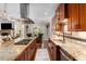 Open-concept kitchen featuring granite countertops, stainless appliances and a view to an adjacent living room at 580 Grimsby Ct, Suwanee, GA 30024