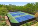 An aerial view of 4 outdoor tennis courts lined by lush green trees at 580 Grimsby Ct, Suwanee, GA 30024