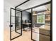 Home office through steel and glass doors with light wood floors and sleek furniture at 650 Jones Rd, Roswell, GA 30075
