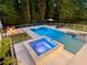 Stunning backyard retreat with a sparkling pool, hot tub, fire pit, and ample seating areas surrounded by mature trees at 650 Jones Rd, Roswell, GA 30075