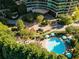 Aerial view of sparkling pool with lounge chairs, umbrellas, lush landscaping, and a circular driveway at 700 Park Regency Ne Pl # 1407, Atlanta, GA 30326