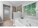 Bright bathroom featuring a soaking tub, glass shower, and scenic outdoor views at 2155 Mindy Ln, Cumming, GA 30041