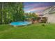 Spacious backyard featuring a wooden deck, above-ground pool, and mature trees, perfect for outdoor activities at 411 Hollis Cir, Dallas, GA 30157