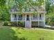 Charming home with a welcoming front porch, manicured lawn, and mature trees enhancing curb appeal at 411 Hollis Cir, Dallas, GA 30157