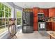 Bright kitchen features stainless steel appliances, warm wood cabinetry, and large windows for natural light at 411 Hollis Cir, Dallas, GA 30157