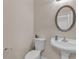 Powder room with white pedestal sink, toilet, oval mirror, and neutral wall color at 4567 Hickory Forest Nw Dr, Acworth, GA 30102