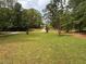 A well-maintained front yard features lush green grass, mature trees, and a long driveway leading to the house at 595 Crowell Rd, Porterdale, GA 30014