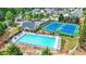 Aerial view of a community pool with lounge chairs, a clubhouse, and two tennis courts, surrounded by green spaces at 1544 Overview Cir, Lawrenceville, GA 30044