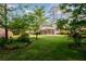 Beautifully landscaped backyard with mature trees, lush green lawn, and a covered patio at 3407 Larch Pine Dr, Duluth, GA 30096