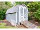 A gray storage shed features a wooden ramp, white trim and cross-buck doors, providing outdoor storage at 3407 Larch Pine Dr, Duluth, GA 30096