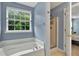 Bright bathroom featuring a soaking tub, separate shower, and a window with green outdoor views at 408 Sam Cobb Ct, Woodstock, GA 30188